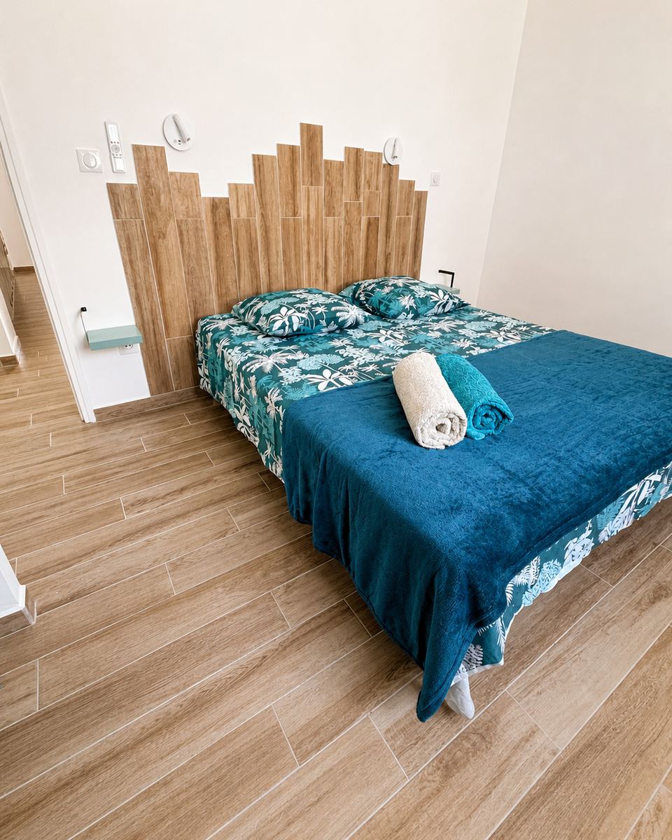 Chambre climatisée avec tête de lit en bois et linge turquoise